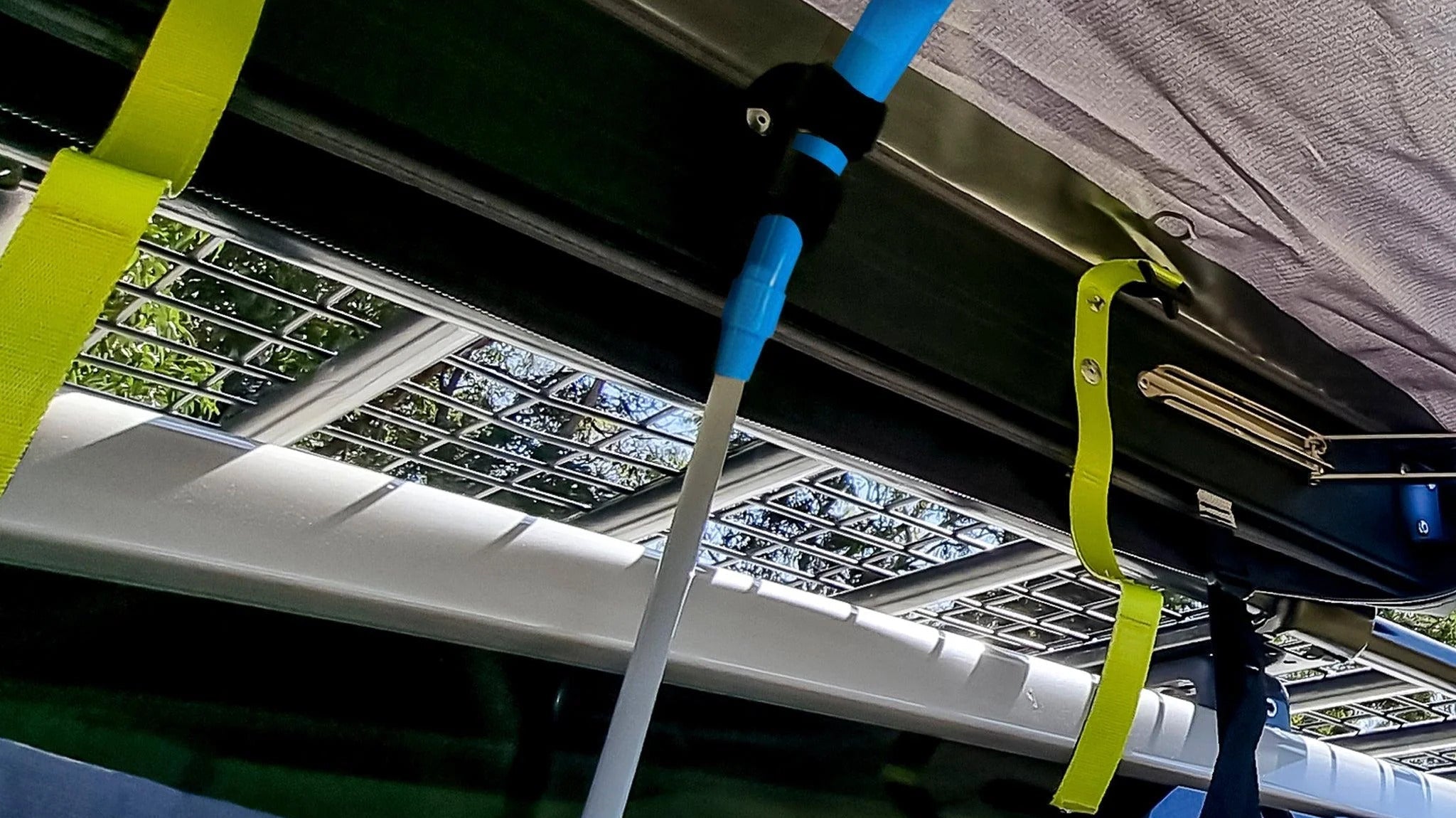 A blue tool hangs from the top of a tent, showcasing a 12V portable camping shower for outdoor convenience.