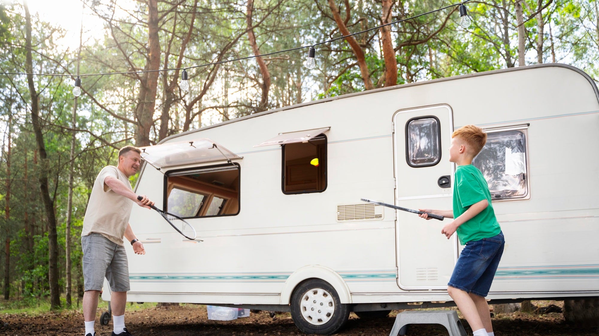 father and son playing next to caravan