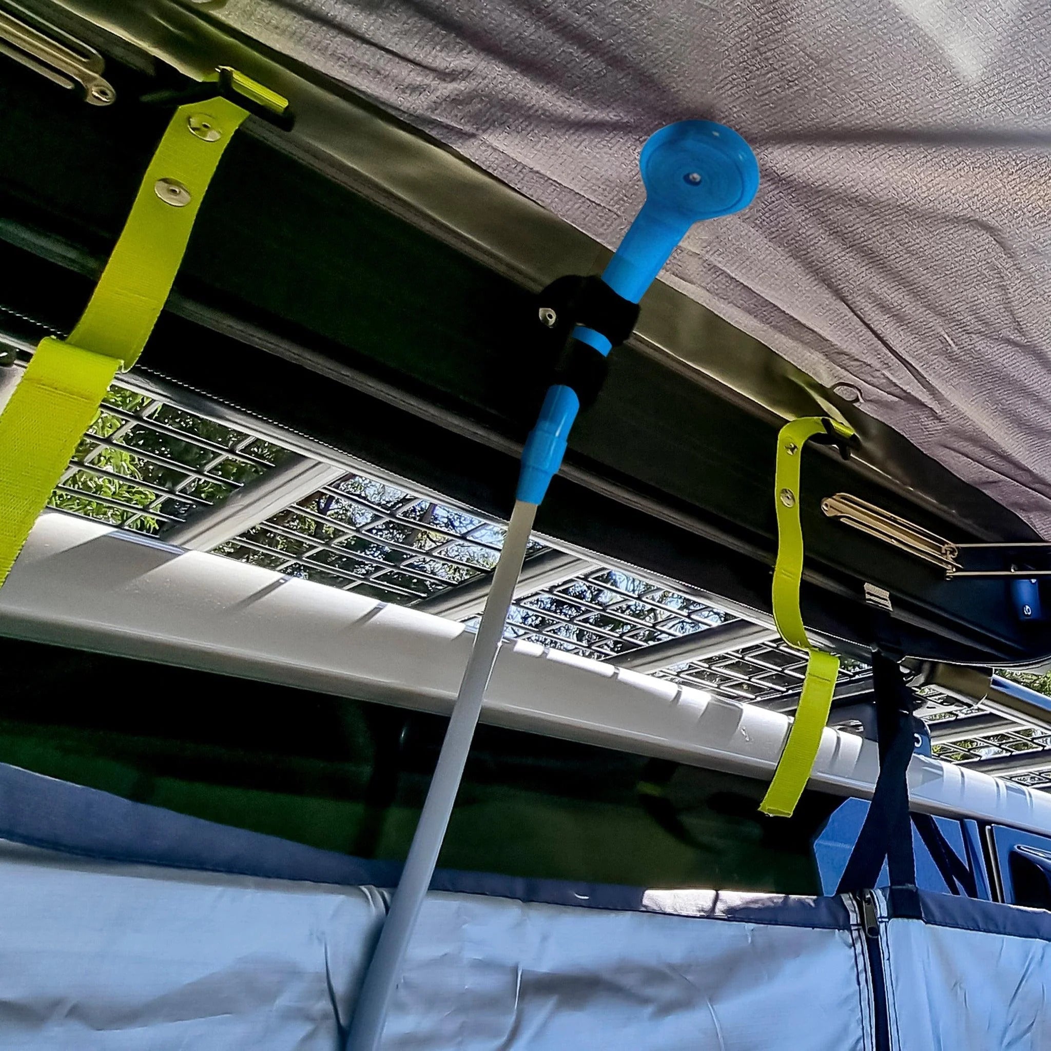 A blue tool hangs from the top of a tent, showcasing a 12V portable camping shower for outdoor convenience.