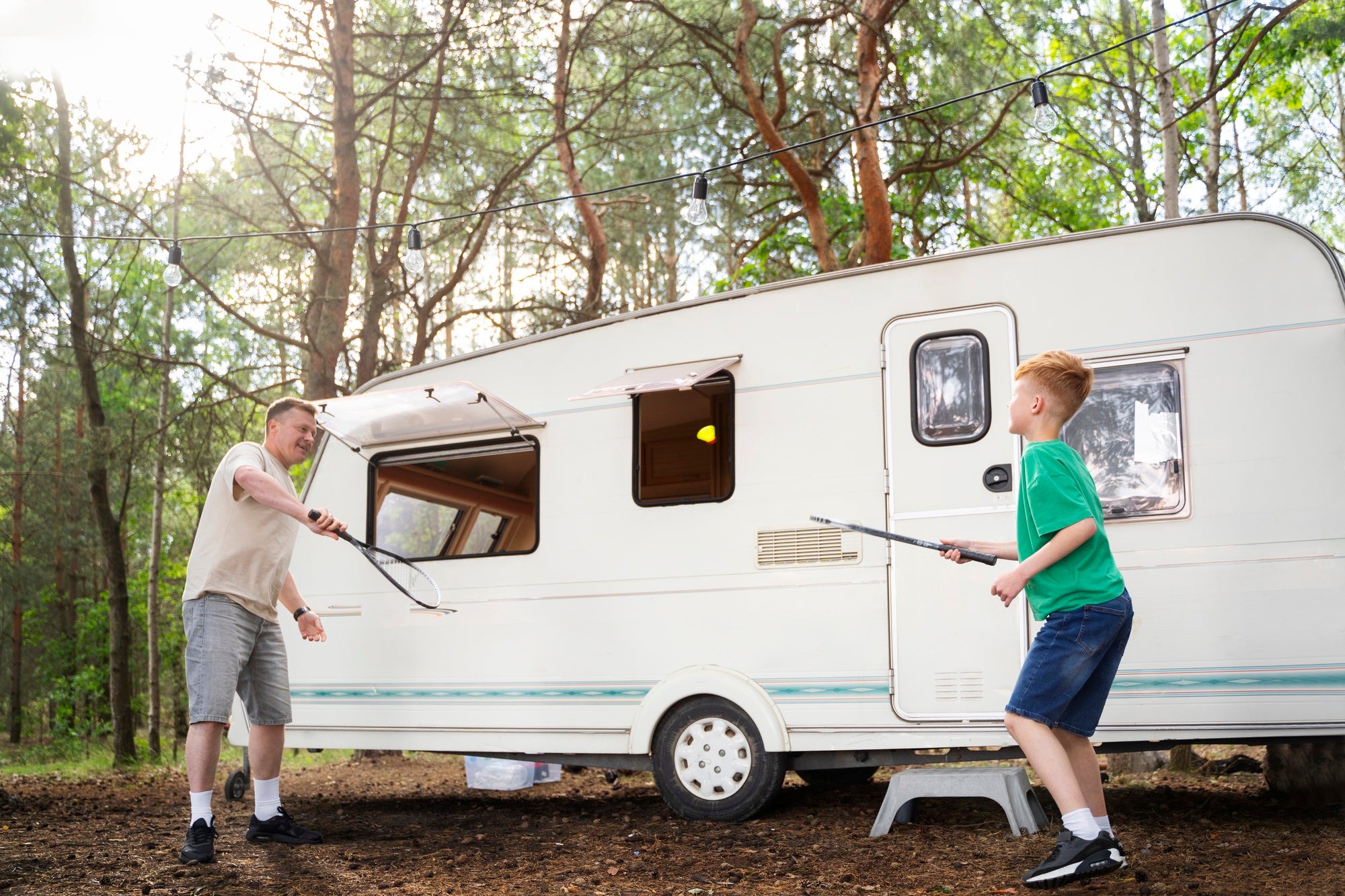 father and son playing next to caravan